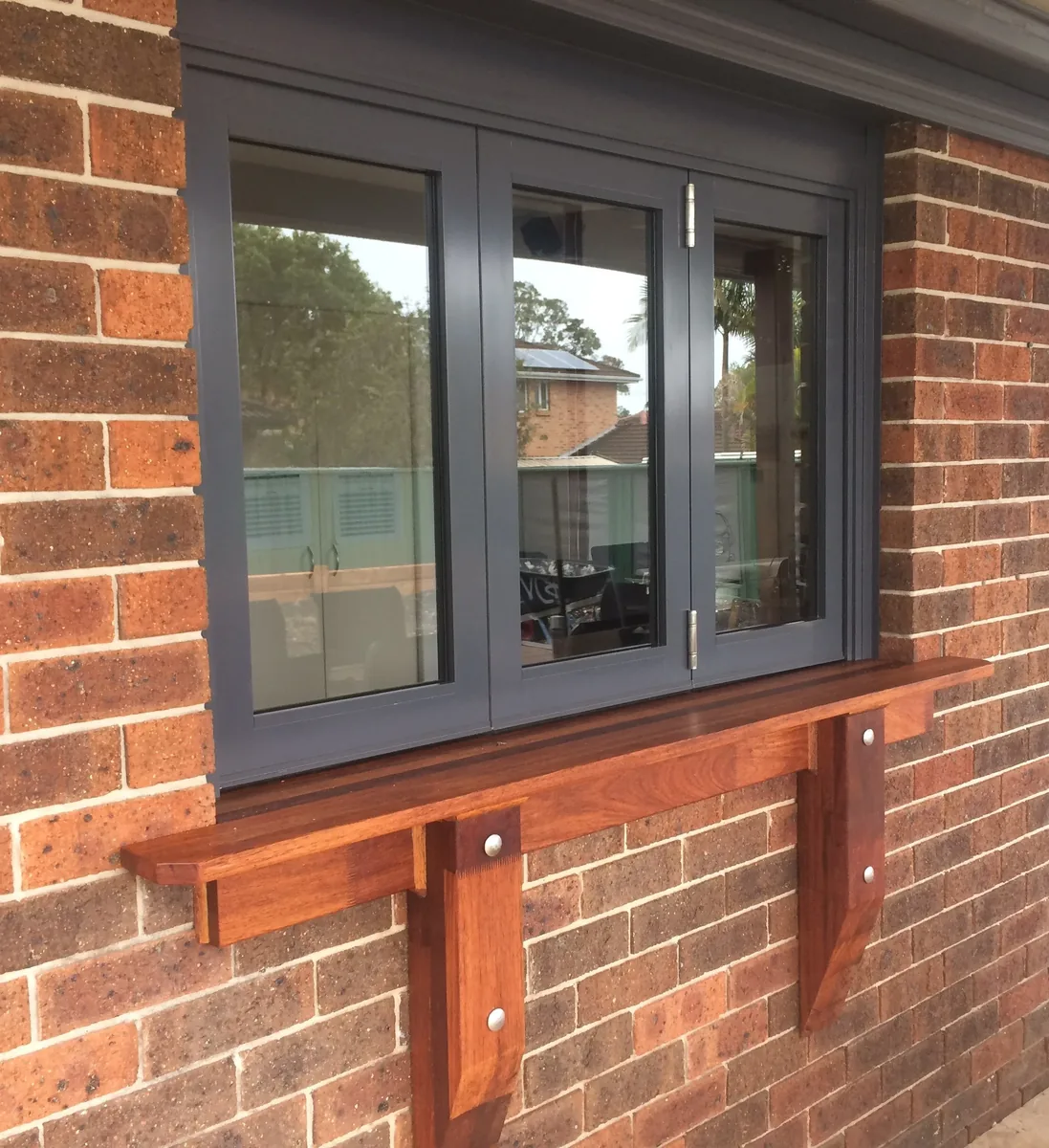 Aluminium-framed window fitted into a brick wall with a timber sill