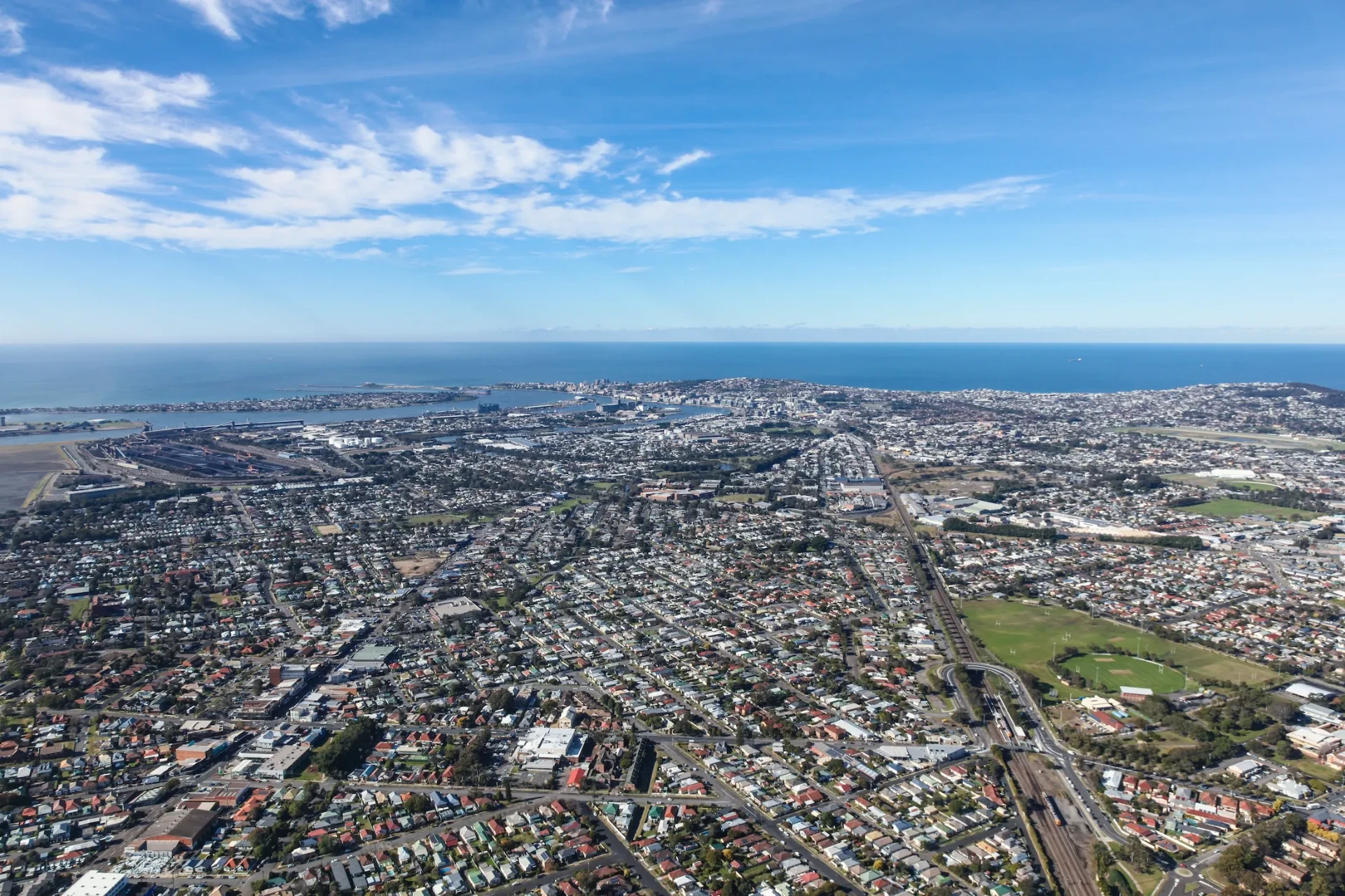 Aerial view over Newcastle suburbs toward the harbour entrance and coastline