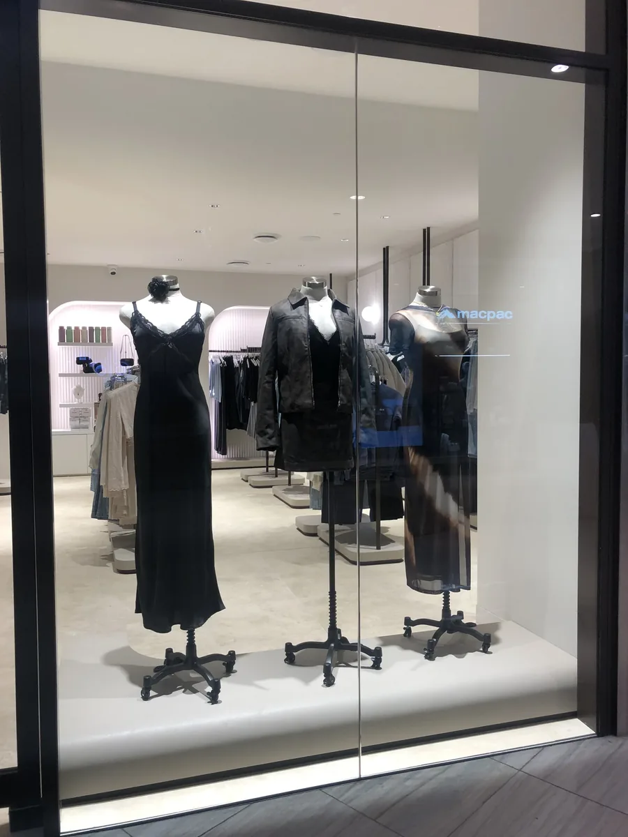 Retail display window glazing framing mannequins inside a store
